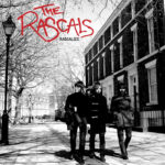 Sorti pour la première fois en vinyle à l’occasion du Record Store Day 2026 The Rascals est un trio indie rock britannique formé en 2006 par Miles Kane (guitare et chant), Joe Edwards (basse) et Greg Mighall (batterie), originaires de Wirral dans le Merseyside. Avant de former The Rascals, les trois membres ont passé leurs années de formation à jouer ensemble dans The Little Flames, acquérant une expérience précieuse en tournant avec des contemporains de renom tels que The Coral, The Zutons et, surtout, Arctic Monkeys. C’est en assurant la première partie d’Arctic Monkeys, inspirés par leur esprit farouchement indépendant, leur philosophie DIY et leur refus de tout compromis, que le trio a décidé de suivre son instinct et de se lancer seul. En septembre 2006, Kane, Edwards et Mighall ont commencé à écrire et à improviser en trio, donnant naissance à The Rascals. Le groupe a rapidement développé un son ancré dans des mélodies pop puissantes et des fioritures psychédéliques, mais se distinguant par un courant sous-jacent plus sombre et plus introspectif. Influencée par des artistes tels que Scott Walker, leur musique possède une qualité épique et grandiose, tandis que leurs paroles évoquent souvent une atmosphère à la David Lynch. Comme l’explique Kane, The Rascals ne se sont jamais contentés de rester à la surface, préférant explorer des thèmes plus subtils et obscurs qui se révèlent au fil du temps. Bien que Miles Kane soit largement connu pour son travail avec Alex Turner dans The Last Shadow Puppets, The Rascals représentent un exutoire plus direct, axé sur la guitare. Alors que The Last Shadow Puppets s’appuie sur des arrangements pop et des sections de cordes sophistiqués des années 60, The Rascals laisse la parole aux guitares. Leur premier album, Rascalize, sorti à l’origine en 2008, comprend douze titres énergiques de rock psychédélique et indépendant qui s’inspirent largement des sons des années 60 tout en restant ancrés dans la scène indie britannique de la fin des années 2000. Sorti chez Deltasonic Records, Rascalize montre clairement l’influence de leurs collègues du label et de leurs pairs tels que The Coral, ainsi que des échos de groupes comme The Inspiral Carpets. Des morceaux remarquables tels que « The Glorified Collector », « Does Your Husband Know That You’re On The Run? » et le single « Freakbeat Phantom » mettent en évidence le talent du groupe pour les refrains accrocheurs, les effets de guitare superposés et les rythmes entraînants. Largement considéré comme l’un des meilleurs premiers albums indie de 2008, Rascalize a consolidé la place de The Rascals dans le paysage indie britannique. Aujourd’hui, avec sa toute première sortie en vinyle pour le Record Store Day 2026, l’album offre aux fans de longue date comme aux nouveaux auditeurs l’occasion de redécouvrir un disque audacieux et énergique qui capture un moment unique dans l’histoire du rock indie britannique. Tracklisting 1. Rascalize 2. Out Of Dreams 3. Bond Girl 4. The Glorified Collector 5. Fear Invicted Into The Perfect Stranger 6. Does Your Husband Know That You’re On The Run? 7. I’d Be Lying To You 8. Freakbeat Phantom 9. People Watching 10. Stockings To Suit 11. How Do I End This? 12. I’ll Give You Sympathy